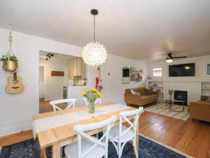 Dining space featuring a wood stove, ceiling fan, and wood-type flooring