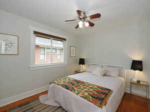 Bedroom with dark hardwood / wood-style floors and ceiling fan