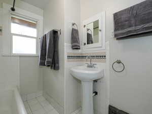 Bathroom with a bathtub, tile patterned floors, and tile walls