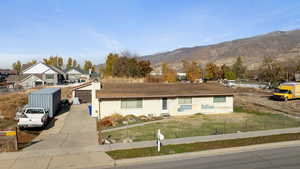 Ranch-style home with a mountain view, a garage, an outbuilding, and a front lawn