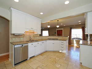 Kitchen with pendant lighting, sink, white cabinetry, kitchen peninsula, and stainless steel appliances