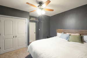 Carpeted bedroom with a closet and ceiling fan