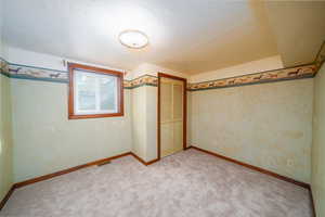 Unfurnished bedroom with a textured ceiling, carpet floors, and a closet