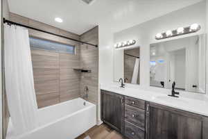 Bathroom featuring hardwood / wood-style floors, vanity, and shower / bath combination with curtain