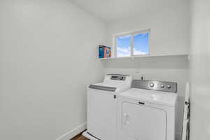 Clothes washing area with washer and clothes dryer and dark hardwood / wood-style floors