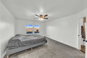 Bedroom with ceiling fan and dark colored carpet