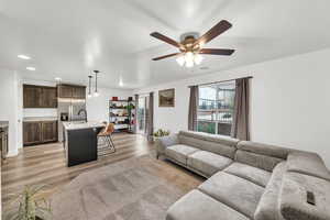 Living room with ceiling fan, light wood-type flooring, and a textured ceiling