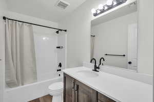 Full bathroom featuring shower / bath combination with curtain, vanity, wood-type flooring, and toilet