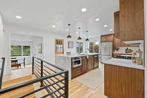 Kitchen featuring light hardwood / wood-style flooring, a healthy amount of sunlight, decorative light fixtures, and appliances with stainless steel finishes