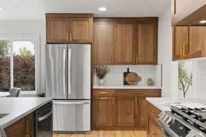 Kitchen with backsplash, light hardwood / wood-style floors, and stainless steel appliances