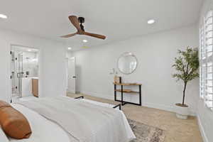 Bedroom with ensuite bath, light carpet, and ceiling fan