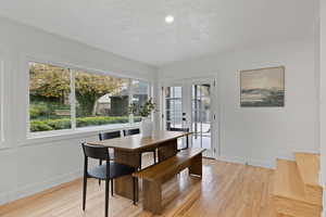 Dining area with french doors, a textured ceiling, and light hardwood / wood-style floors