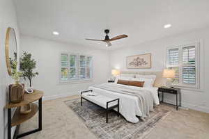 Carpeted bedroom featuring multiple windows and ceiling fan