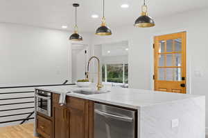 Kitchen featuring pendant lighting, sink, an island with sink, and light hardwood / wood-style floors