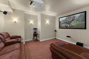 Carpeted home theater with a textured ceiling