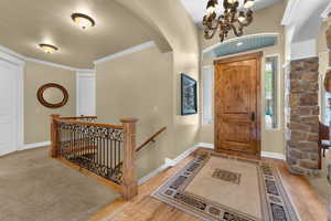 Entryway with light hardwood / wood-style floors, ornamental molding, and a chandelier