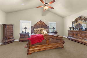 Carpeted bedroom featuring ceiling fan and lofted ceiling