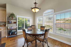 Dining room with light hardwood / wood-style flooring and lofted ceiling