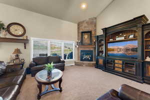 Carpeted living room with a stone fireplace and high vaulted ceiling