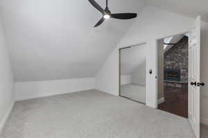 Bonus room featuring carpet flooring, ceiling fan, lofted ceiling, and a fireplace