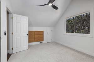 Additional living space featuring light carpet, ceiling fan, and lofted ceiling