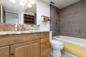 Full bathroom featuring tile patterned flooring, vanity, toilet, and tiled shower / bath