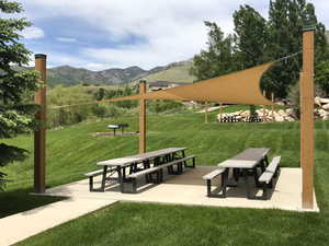 View of community picnic area with a mountain view and a lawn