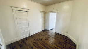 Unfurnished bedroom featuring a textured ceiling, crown molding, and dark wood-type flooring