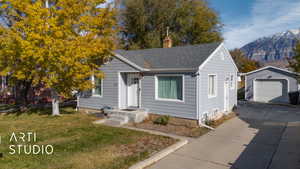 Bungalow-style home with a mountain view, a garage, an outbuilding, and a front yard