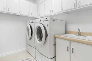 Laundry room with cabinets, separate washer and dryer, and sink