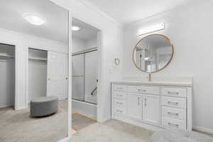 Bathroom featuring shower / bath combination with glass door, vanity, and crown molding