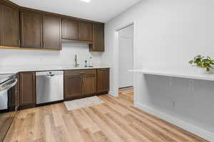 Kitchen with sink, stainless steel appliances, dark brown cabinets, and light hardwood / wood-style floors