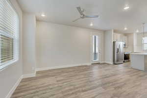 Unfurnished living room featuring ceiling fan, a healthy amount of sunlight, and light hardwood / wood-style flooring