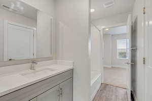 Bathroom featuring shower / tub combination, hardwood / wood-style floors, and vanity