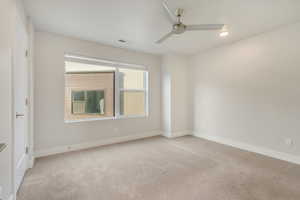 Empty room featuring ceiling fan and light colored carpet