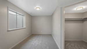 Unfurnished bedroom featuring carpet floors, a textured ceiling, and a closet