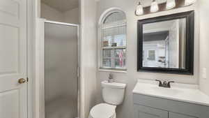 Bathroom with vanity, a shower with shower door, and toilet