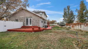 Rear view of house featuring solar panels, cooling unit, a lawn, and a wooden deck