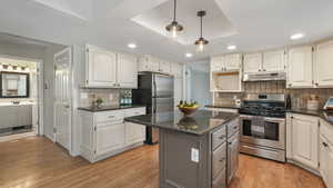 Kitchen with backsplash, a center island, light hardwood / wood-style flooring, and appliances with stainless steel finishes