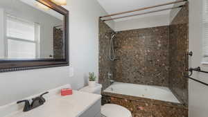 Full bathroom featuring vanity, tiled shower / bath combo, and toilet