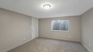 Unfurnished room with a textured ceiling and light carpet