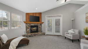 Sitting room featuring carpet, vaulted ceiling, and a stone fireplace