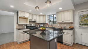 Kitchen with a center island, backsplash, sink, light hardwood / wood-style flooring, and stainless steel appliances