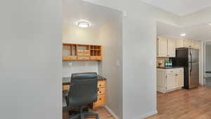 Office with built in desk and light hardwood / wood-style floors