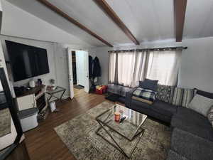 Living room featuring vaulted ceiling with beams and dark hardwood / wood-style floors