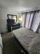 Carpeted bedroom featuring brick wall and a textured ceiling