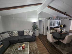 Living room with vaulted ceiling with beams, dark hardwood / wood-style floors, and a textured ceiling