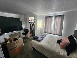 Bedroom featuring a walk in closet, a textured ceiling, carpet floors, and a closet