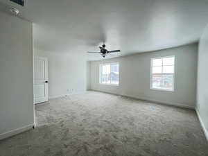 Spare room with carpet flooring, ceiling fan, and a healthy amount of sunlight