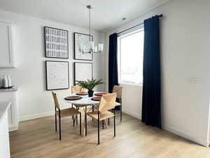 Dining room with light wood-type flooring and a notable chandelier